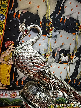 indian peacock sculpture artifact in silver metal with indian folk art is in background Editorial Stock Photo