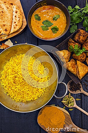 Indian pilau rice in balti dish served with chicken tikka masala curry and side dishes Stock Photo