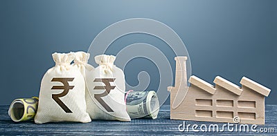 Indian rupee money bags and industrial factory plant. Investments in production and energy industry. Concession auction tender. Stock Photo