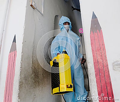 An Indian sanitary worker in a protective suit conducting disinfection of a school during COVID-19 Editorial Stock Photo