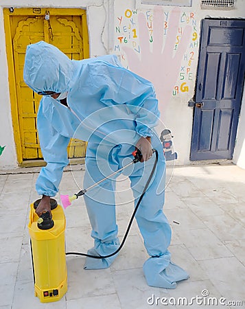 Indian sanitary worker in a protective suit conducting disinfection of a school during COVID-19 Editorial Stock Photo