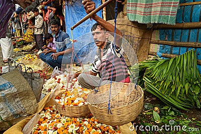 Indian seller weighs flowers by scales on Flower market at Mallick Ghat in Kolkata. India Editorial Stock Photo