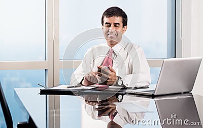 Senior manager in skyscraper office checking smart phone Stock Photo