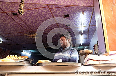 An Indian shop owner selling fried street food in a street in Pushkar, India Editorial Stock Photo