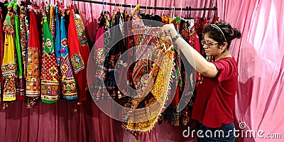 an indian shopkeeper girl holded traditional women outfits at garment store Editorial Stock Photo