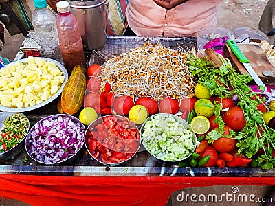 Indian street food vendor selling spicy gram chole mixture garnished with freshly cut onion,cucumber chilli and tomatoindian Stock Photo