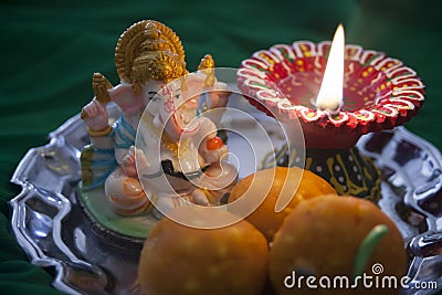 Indian sweet laddu with a prayer lamp and Ganesha statue Stock Photo