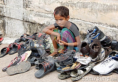 Indian unidentified girl watching the foot wear out side the Hindu temple Editorial Stock Photo