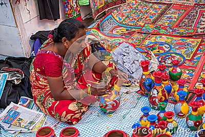 An Indian Unidentified middle-aged woman paints on colourful handicraft items for sale in Kolkata in handicrafts trade fair. It is Editorial Stock Photo
