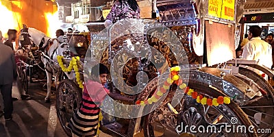 an indian village boy pushing silver carriage ride during dussehra festival in India Editorial Stock Photo