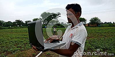 An indian village farmer operating laptop computer system in agriculture background Editorial Stock Photo