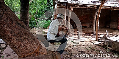 An indian village farmer operating laptop system seating at animals pot Editorial Stock Photo