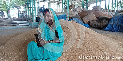 An indian village farmer woman looking movie on mobile phone at agriculture market Editorial Stock Photo