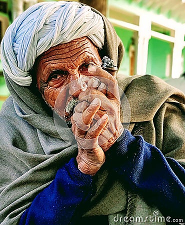 Indian village old man smoking Ganja Marihuana with chillum/hukkah in Rajasthan& x27;s traditional dress turban on head in winter Editorial Stock Photo