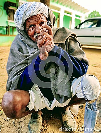 Indian village old man smoking Ganja Marihuana with chillum/hukkah in Rajasthan& x27;s traditional dress turban on head in winter Editorial Stock Photo