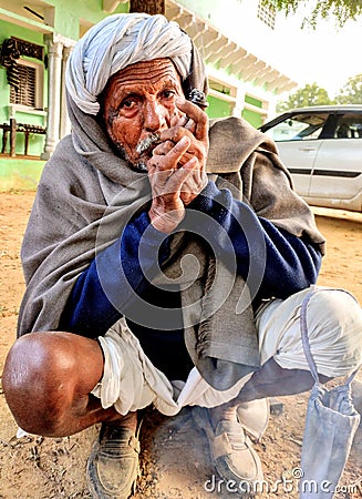 Indian village old man smoking Ganja Marihuana with chillum/hukkah in Rajasthan& x27;s traditional dress turban on head in winter Editorial Stock Photo