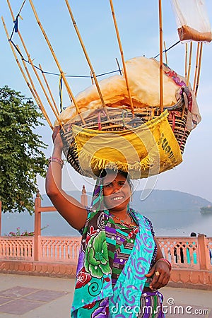 Indian woman with basket on her head selling snacks by Man Sagar Lake in Jaipur, India. Editorial Stock Photo