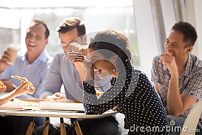 Indian woman laughing eating pizza with diverse coworkers in off Stock Photo