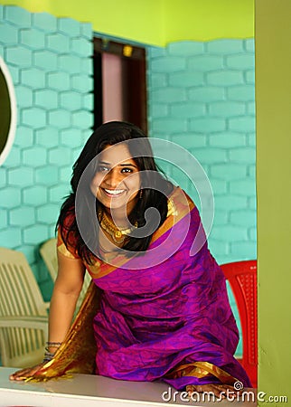 Indian Woman in Purple Saree Bending and Standing Stock Photo