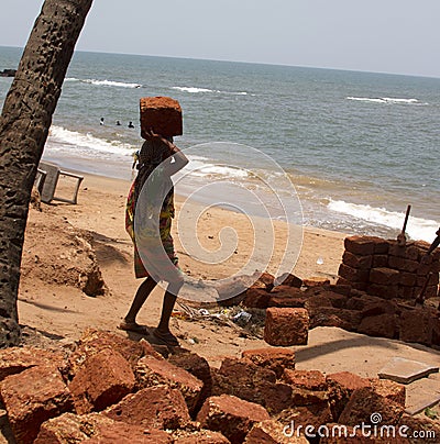The Indian woman in a sari stones for building on the head on a beach. India Goa Editorial Stock Photo