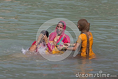 Indian woman wash themselves in the river Ganges in the holy city of Rishikesh, India. Editorial Stock Photo
