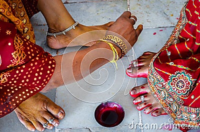 Indian women adorning feet with bright red dye Alta mahavar Stock Photo