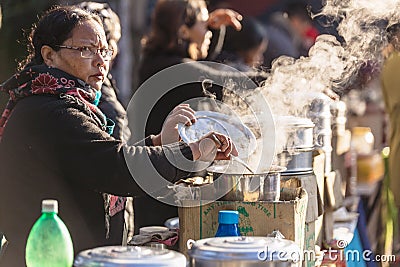 Indian women selling tea with steam from stainless steel bowl in the market near Tiger Hill in winter at Darjeeling, India Editorial Stock Photo