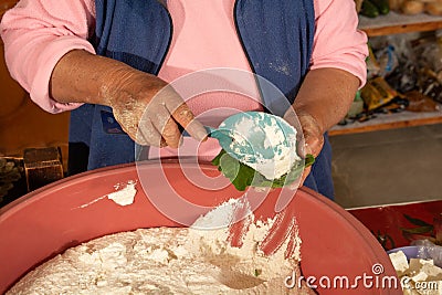 Indigenous woman preparing tamales with masa, stuffed with vegetables, covered by a corn leaf, traditional Mexican food Stock Photo