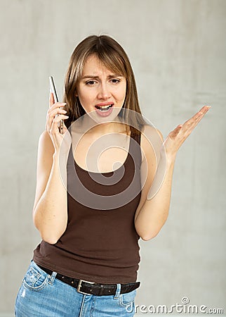 Indignant young girl talking on phone in studio Stock Photo