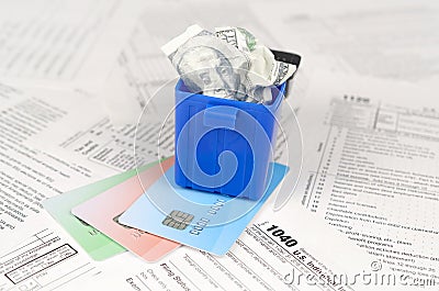 1040 Individual income tax return form and crumpled hundred dollar bill in trash bin on credit cards Editorial Stock Photo