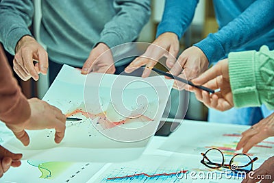 Individuals examining and discussing a complex data visualization sheet among other graphs. Collages working with Stock Photo