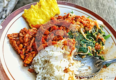 Indonesian Delights: Nasi Pecel with Crispy Fried Tempeh on a Plate Stock Photo