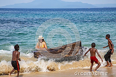 Indonesian funny children with a white lady playing with a huge log in the water Editorial Stock Photo