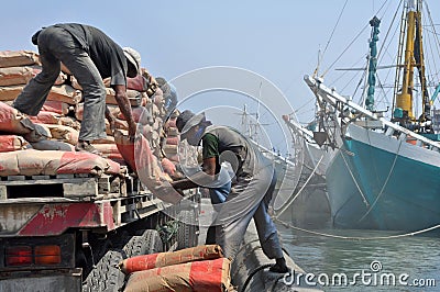 Indonesian port workers unload a ship with a cement bags cargo Editorial Stock Photo