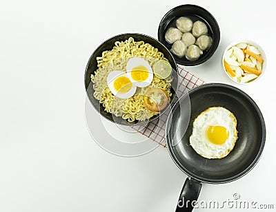 Indonesian Warm noodles served with eggs and fresh tomatoes with meatballs on a black bowl and pickled on a white bowl and eggs on Stock Photo