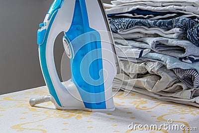 Indoor housework - steam iron and pile of folded clothes Stock Photo