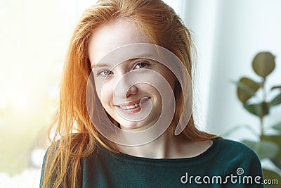 Indoor portrait of pretty smiling red haired young girl, sunny morning light Stock Photo