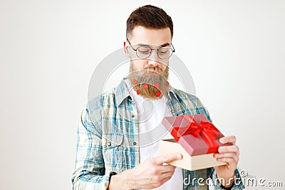 Indoor shot of bearded male model with long thick beard dressed in checkered shirt, opens present box, recieves surprise Stock Photo