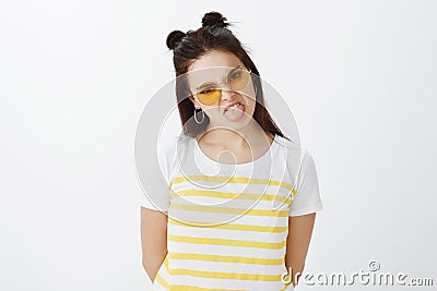 Indoor shot of fashionable picky and moody girlfriend in stylish outfit and glasses with hair buns, sticking out tongue Stock Photo