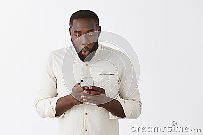 Indoor shot of impressed and amazed good-looking modern African American man with beard and short haircut, holding Stock Photo