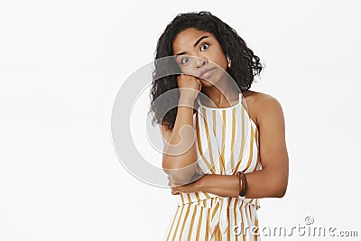 Indoor shot of intense bored and annoyed good-looking dark-skinned female in trendy striped yellow overalls leaning head Stock Photo