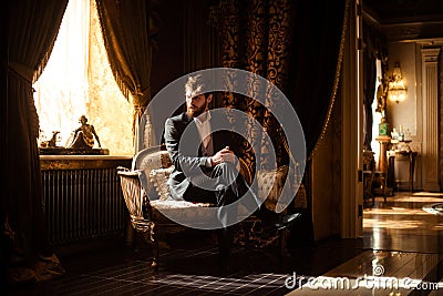 Indoor shot of prosperous intelligent serious businessman sits on comfortable sofa in rich room with luxury furniture Stock Photo