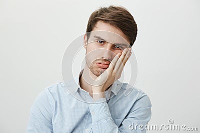 Indoor shot of upset irritated caucasian guy leaning on palm and sighing at camera, being bored and fed up of annoying Stock Photo