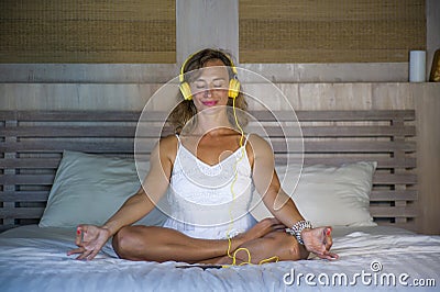 Indoors portrait of beautiful and fit healthy woman 30s practicing yoga listening to music with headphones in bed posing calm and Stock Photo