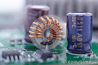 Inductor with motherboard background. Computer board chip circuit. Microelectronics hardware concept. Stock Photo