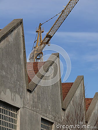 Industrial archeology buildings in the city of Busto Arsizio. Facade of ancient factory shed. Construction crane Stock Photo