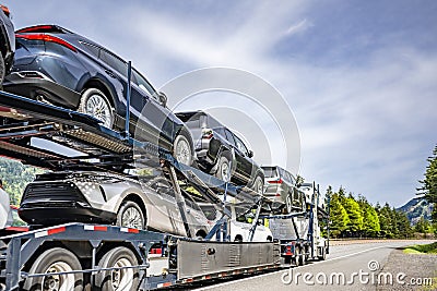 Powerful big rig car hauler semi truck transporting cars on the two level semi trailer with protection skirt running on the Stock Photo