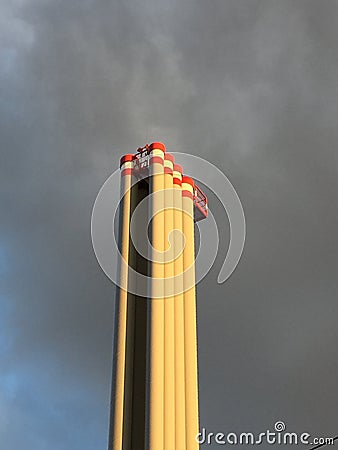 Industrial chimney in front of partly blue, partly polluted sky with dark clouds Stock Photo