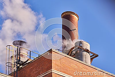 Industrial chimney releasing fumes, steam and polluting gases Stock Photo