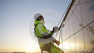 Industrial climber descends the facade of a building on climbing ropes at sunset stock video footage